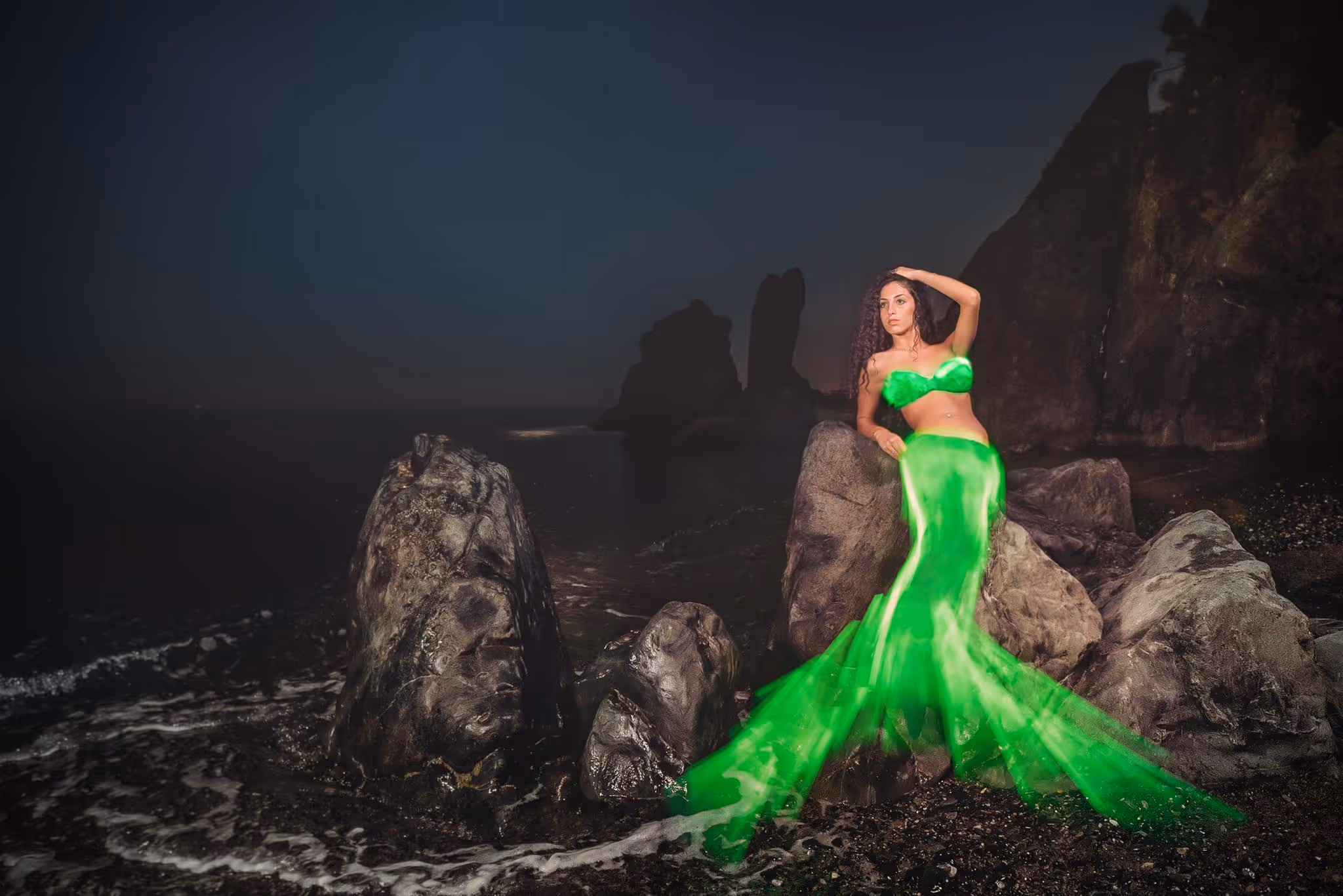 Modella in abito verde davanti a rocce
