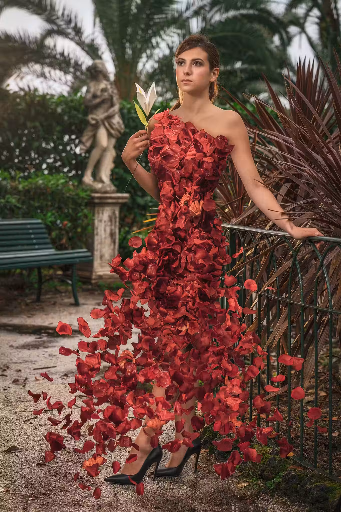 Modella in abito rosso tra foglie tropicali