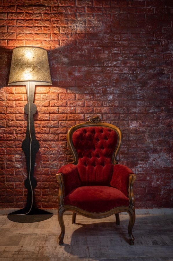 Poltrona rossa e lampada davanti a una parete in mattoni