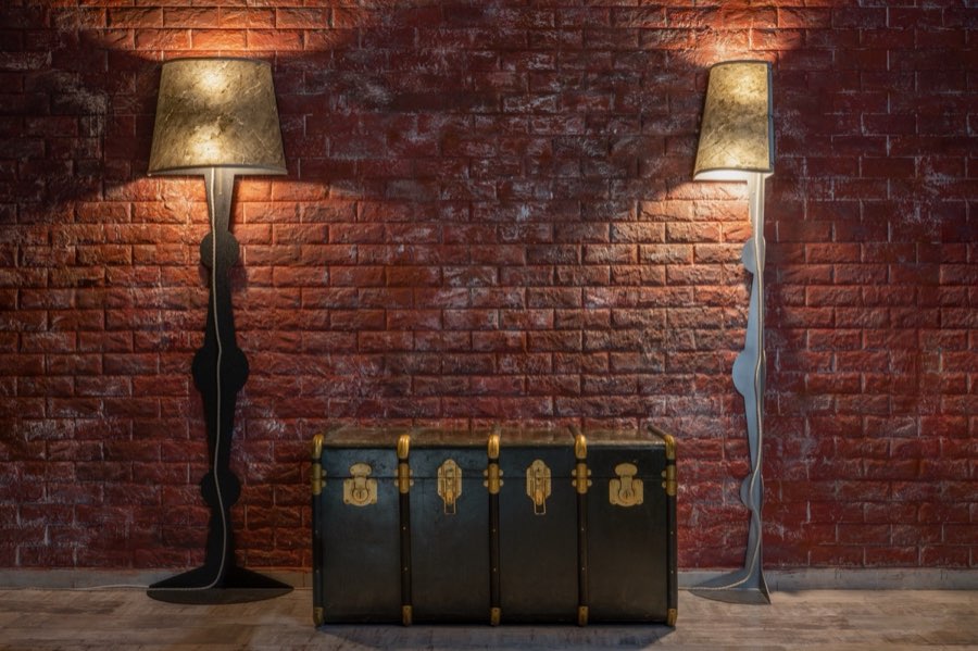 Due lampade e un baule vintage davanti a una parete in mattoni
