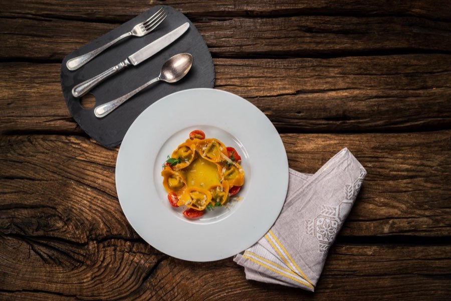 Piatto di pasta ripiena con verdure su tavolo in legno