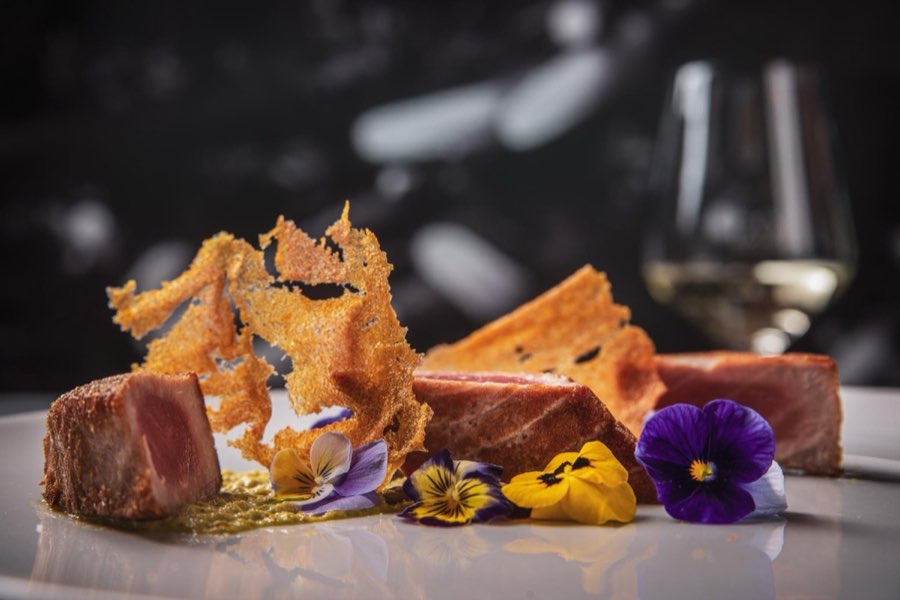 Piatto gourmet con tonno, cialda croccante e fiori eduli