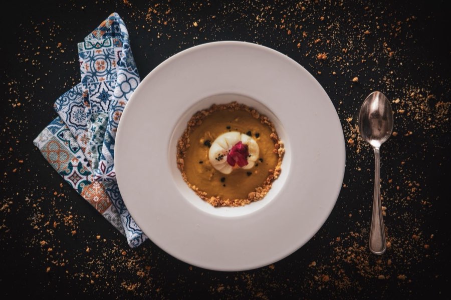 Dessert al cucchiaio con frutta e crumble su piatto bianco