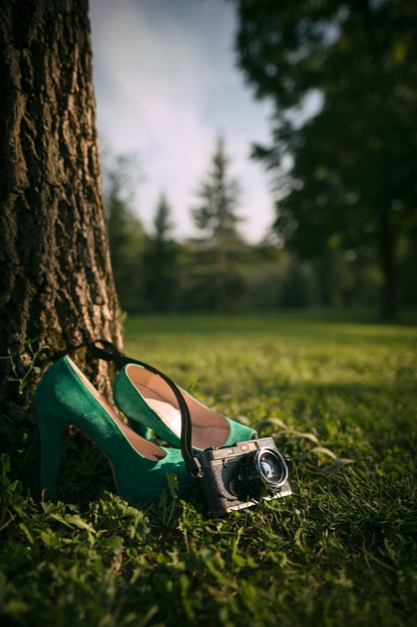 Scarpe verdi con tacco e fotocamera vintage sull’erba